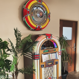 Rock-Ola Bubbler Vinyl 45 Jukebox with an RSB3200 wall speaker in a room with plants and a door.
