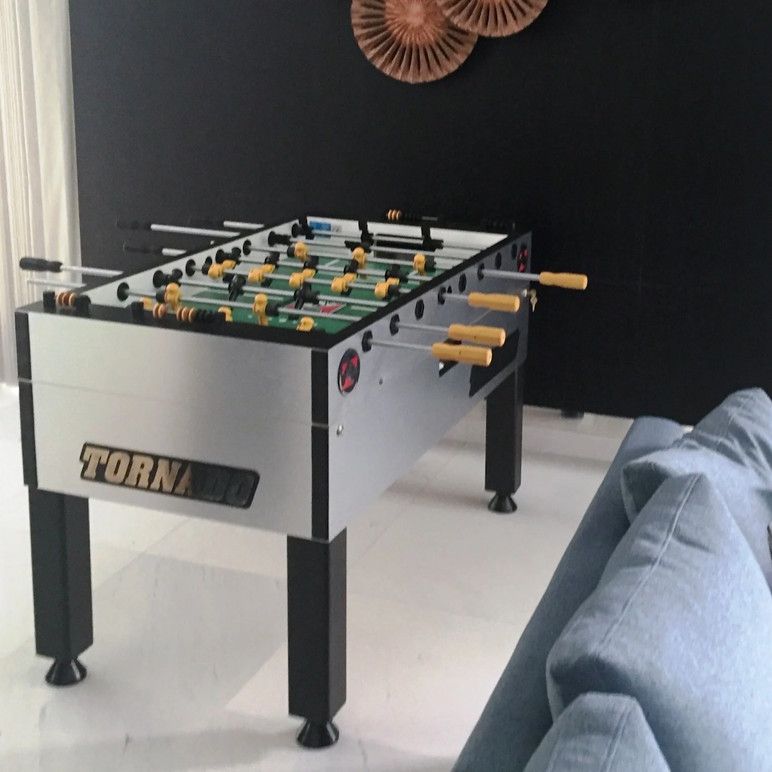 Tornado Foosball table in a room with a dark wall and decorative elements.