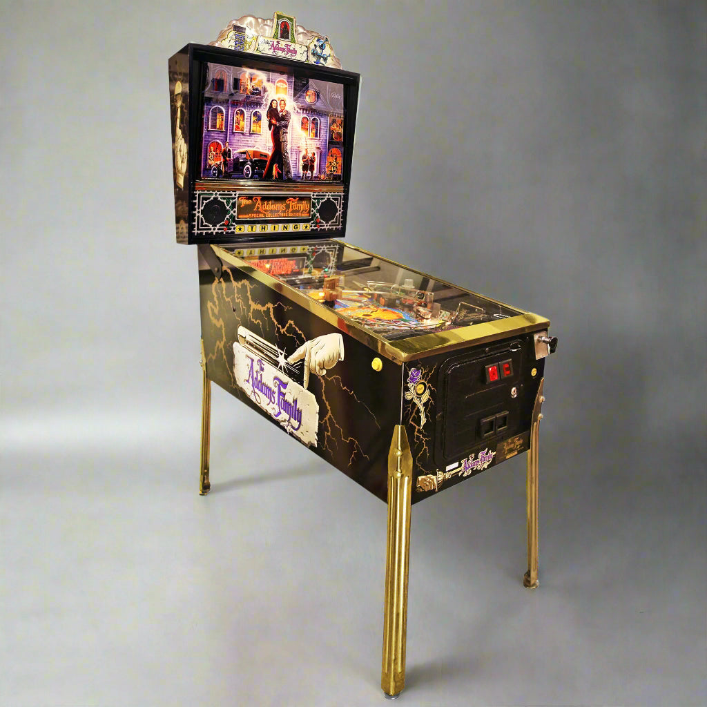 A restored 1994 The Addams Family Gold pinball machine featuring a black and gold color scheme with movie-themed graphics, standing on a pinball table with playfield visible.
